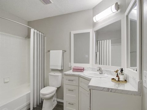A white bathroom with a toilet, sink, and mirror.