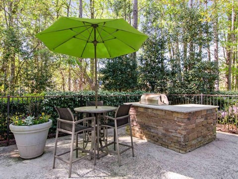 A patio with a table, chairs, and a green umbrella.
