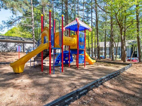 A playground with a yellow slide and a blue and yellow play structure.