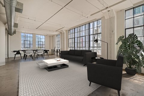A black sofa sits in a spacious room with a white coffee table in front of it.