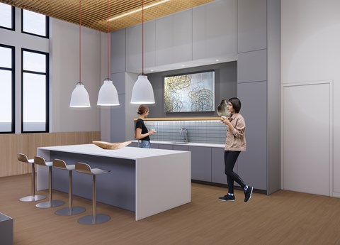 A woman is standing in a modern kitchen with a bar area and a woman is standing at the bar area.