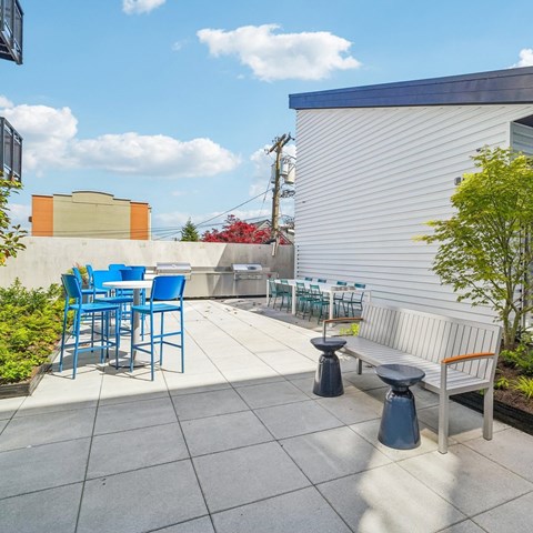 A patio with blue chairs and a white bench.