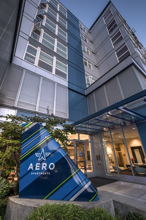 A large blue and white sign that says AERO APARTMENTS in front of a building.