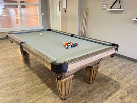 A pool table with a green felt cloth and a white cue ball is in the center of the table.