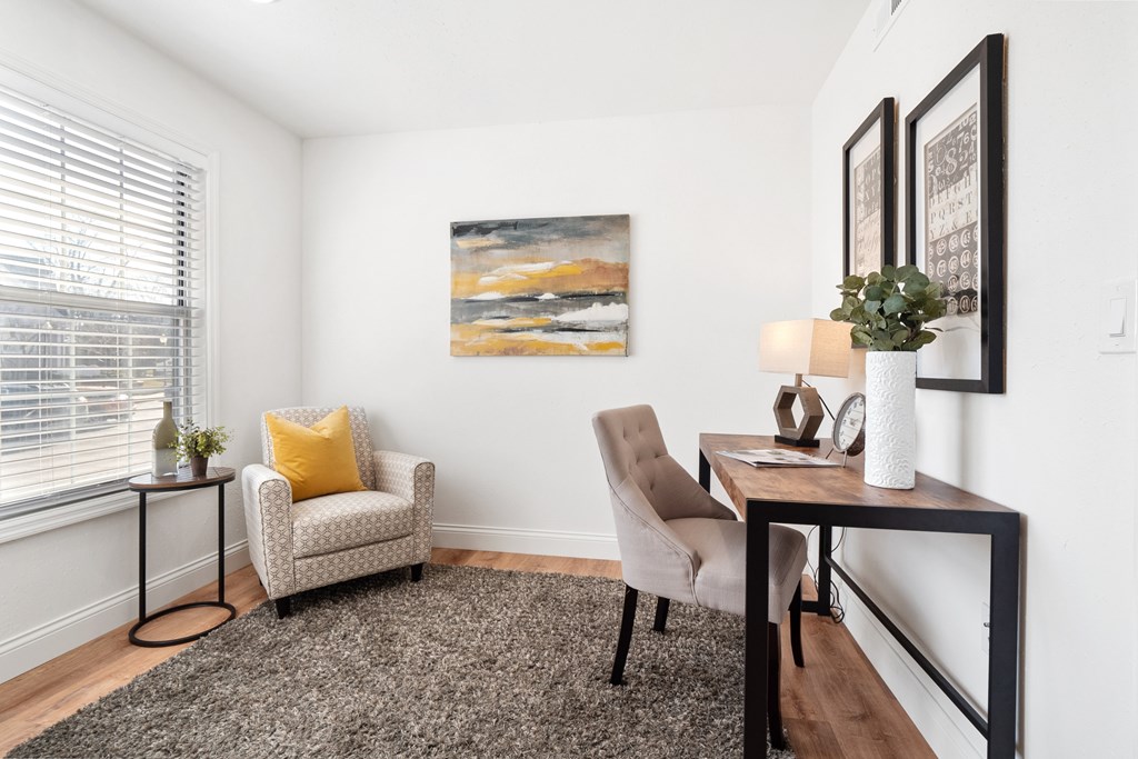 A living room with a chair, a table, and a painting on the wall.