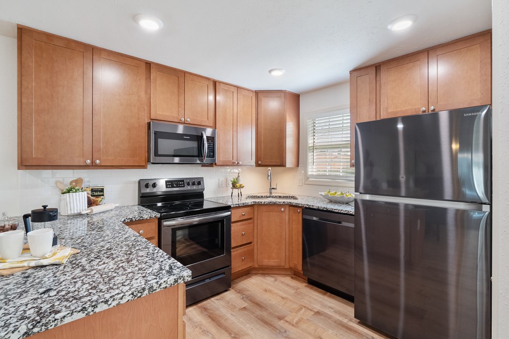 A kitchen with wooden cabinets and a granite countertop.