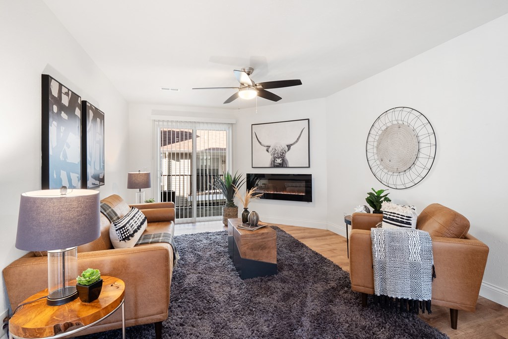 A living room with a fireplace and a fan on the ceiling.