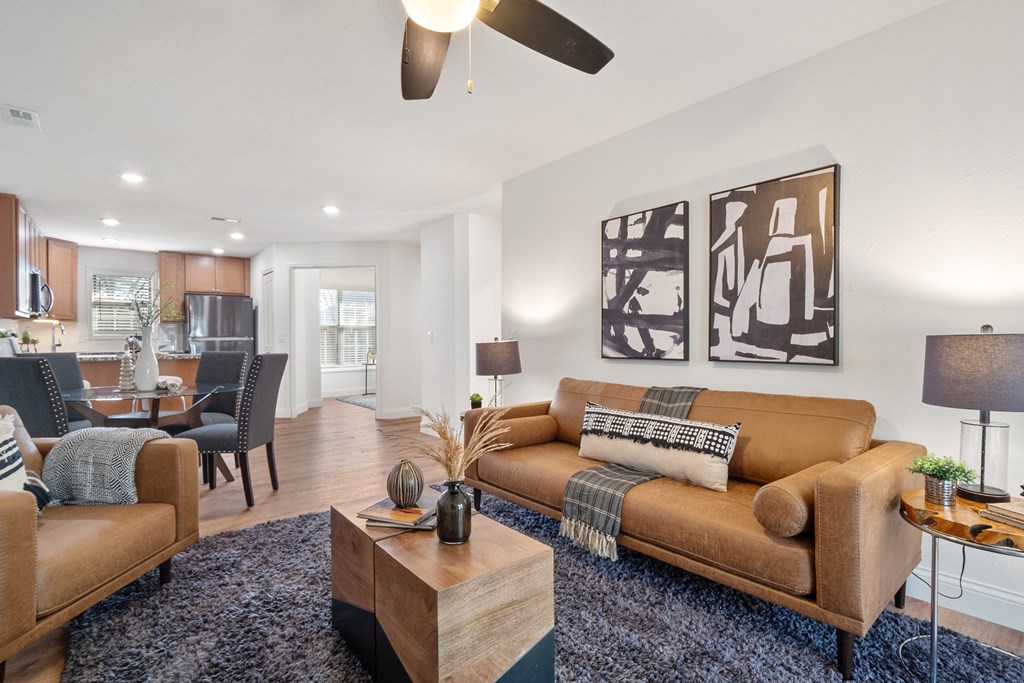 A living room with a brown couch and a ceiling fan.