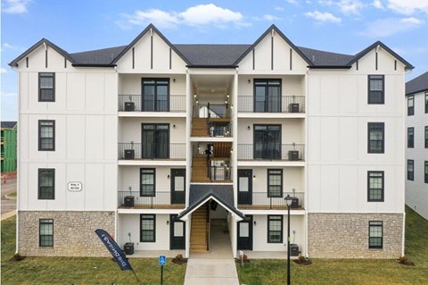 A large white building with a black roof and a balcony on the second floor.