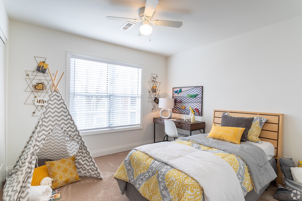 A bedroom with a bed, a teepee, and a desk.
