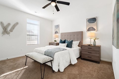A bedroom with a bed, nightstand, and a ceiling fan.