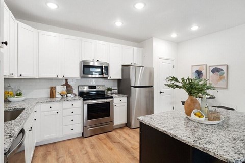 A kitchen with white cabinets and a granite countertop.