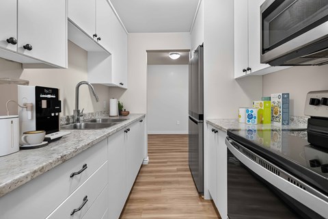 A kitchen with white cabinets and a marble countertop.
