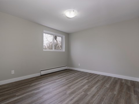 A room with a window and wooden flooring.