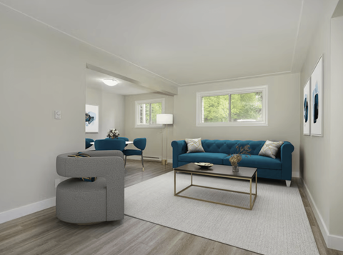 A living room with a blue couch and a grey ottoman.