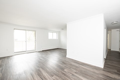 A spacious room with wooden flooring and white walls.