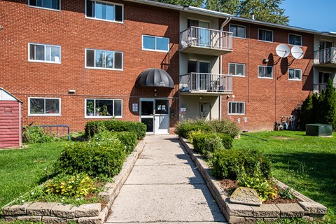 A red brick building with a balcony and a satellite dish on the roof.