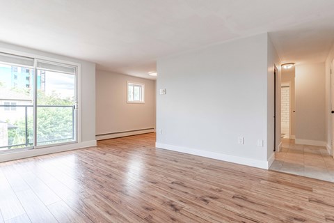 A spacious room with wooden flooring and white walls.