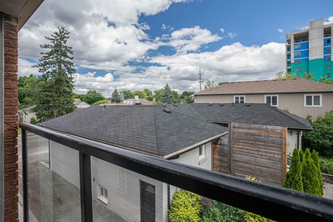 A view from a balcony overlooking a residential area with houses and trees.