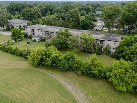 A large house surrounded by trees and a green lawn.