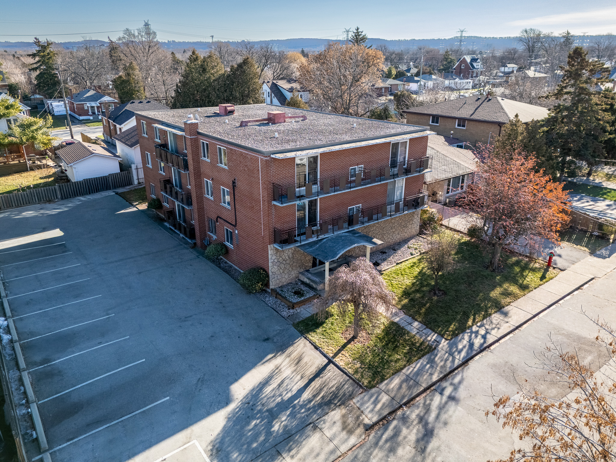 A parking lot is in front of a red brick apartment building.