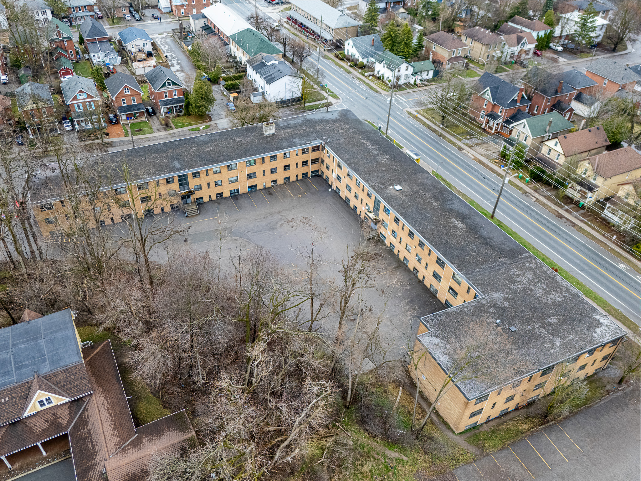 An aerial view of a large, empty, and rundown building with a parking lot in front of it.
