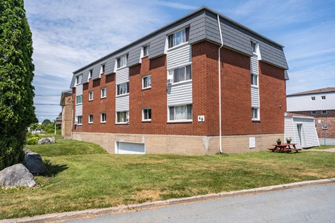 A red brick apartment building with a picnic table in front.