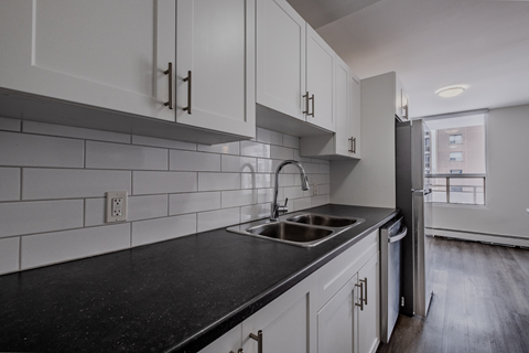 A kitchen with white cabinets and a black countertop.