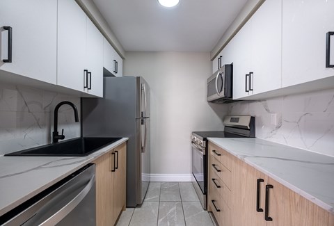 A kitchen with a black fridge and a black counter top.
