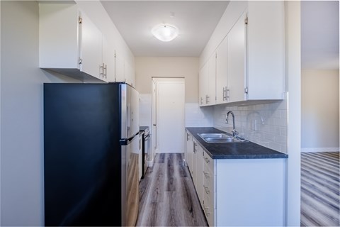 A kitchen with a black refrigerator and white cabinets.