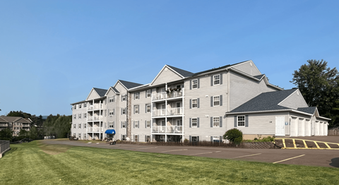 A large building with a grey roof and white walls with balconies on the second floor.