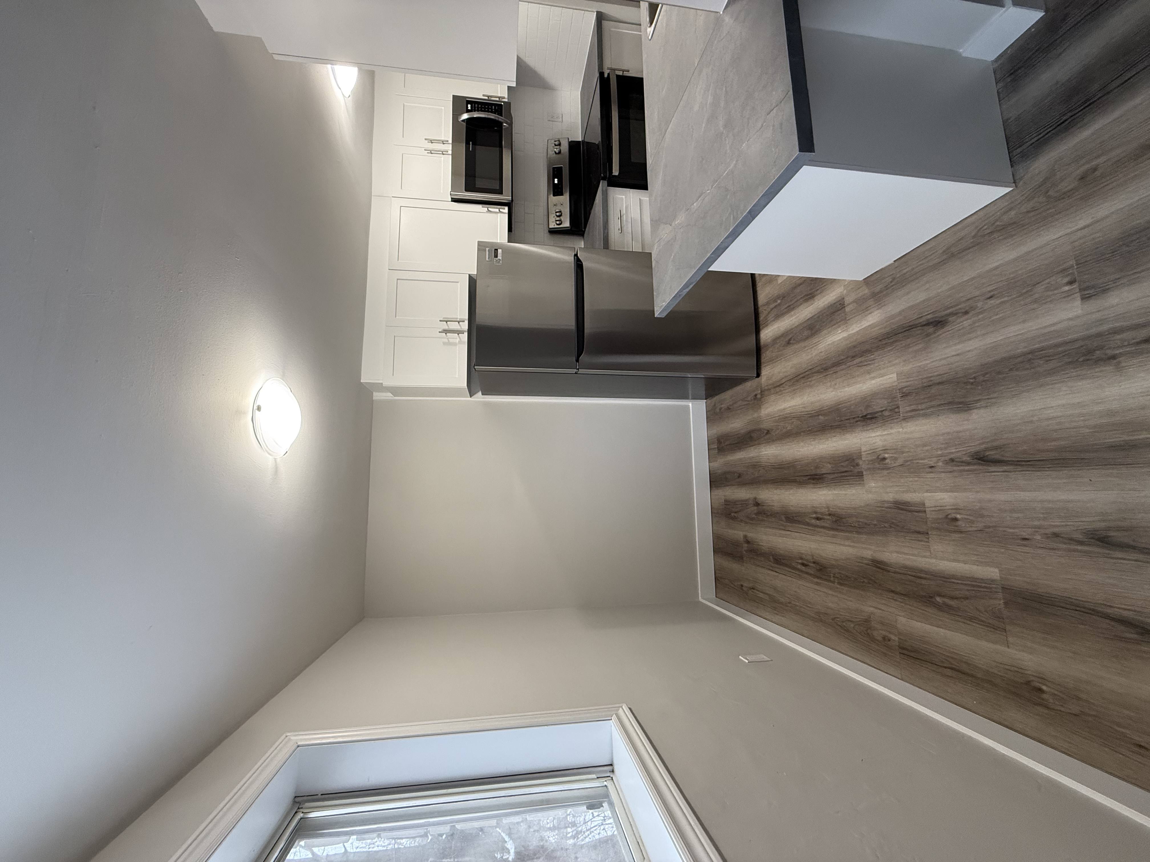 A modern kitchen with a stainless steel refrigerator and wooden wall paneling.