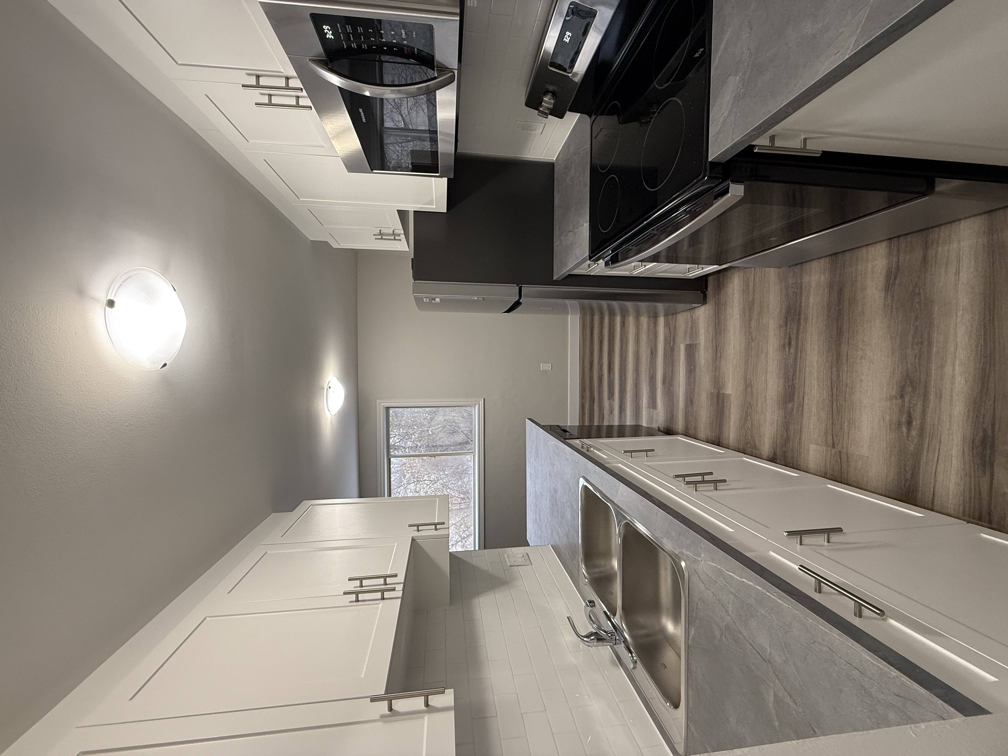 A modern kitchen with stainless steel appliances and white countertops.