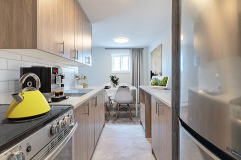 A modern kitchen with a yellow kettle on the stove.