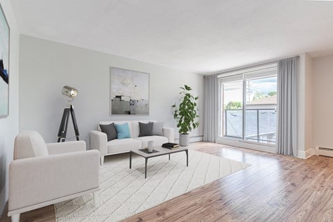 A living room with a white sofa, a white chair, a coffee table, and a painting on the wall.