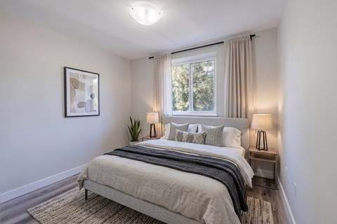 A bedroom with a large bed and a window with curtains.