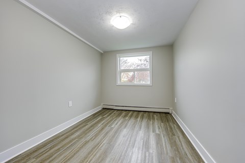 A room with a window and wooden flooring.