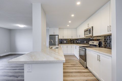 A kitchen with white cabinets and a marble countertop.