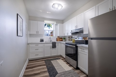 A modern kitchen with white cabinets and stainless steel appliances.