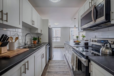 A kitchen with white cabinets and black countertops.