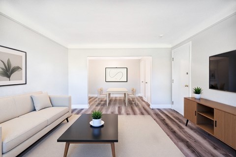 A living room with a couch, coffee table, and a painting on the wall.