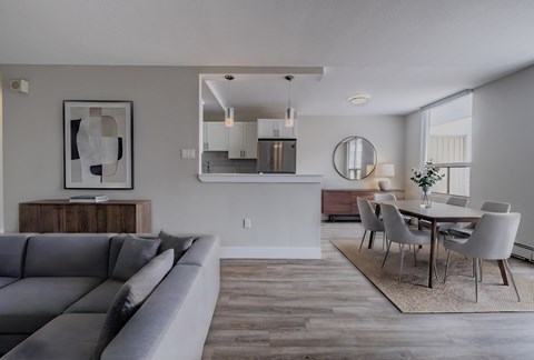 A modern living room with a grey sofa and a dining table set up.
