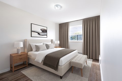A bedroom with a large bed, a nightstand with a lamp, and a window with curtains.
