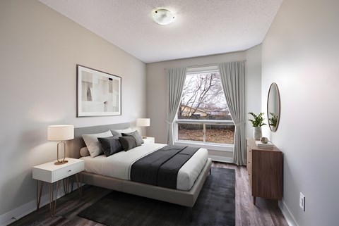 A well-lit bedroom with a large bed and a window with curtains.