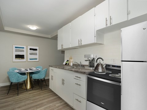 A kitchen with a table and chairs and a fridge.