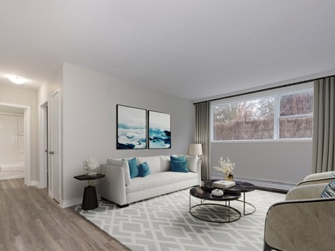 A living room with a white couch and a painting on the wall.