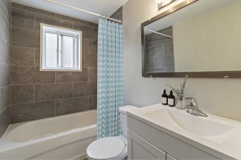 A bathroom with a white toilet, a white sink, a bathtub, and a shower curtain.