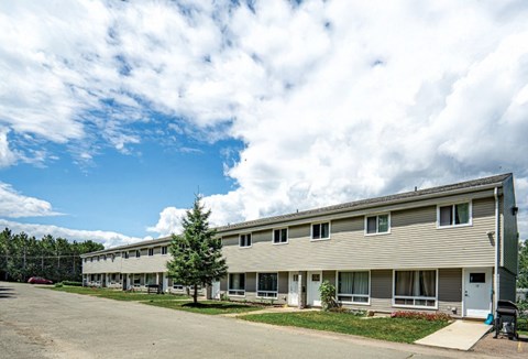 A long building with a parking lot in front.
