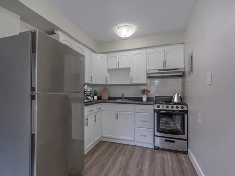 A kitchen with a refrigerator, oven, and cabinets.