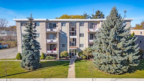A large apartment building with a green lawn in front.